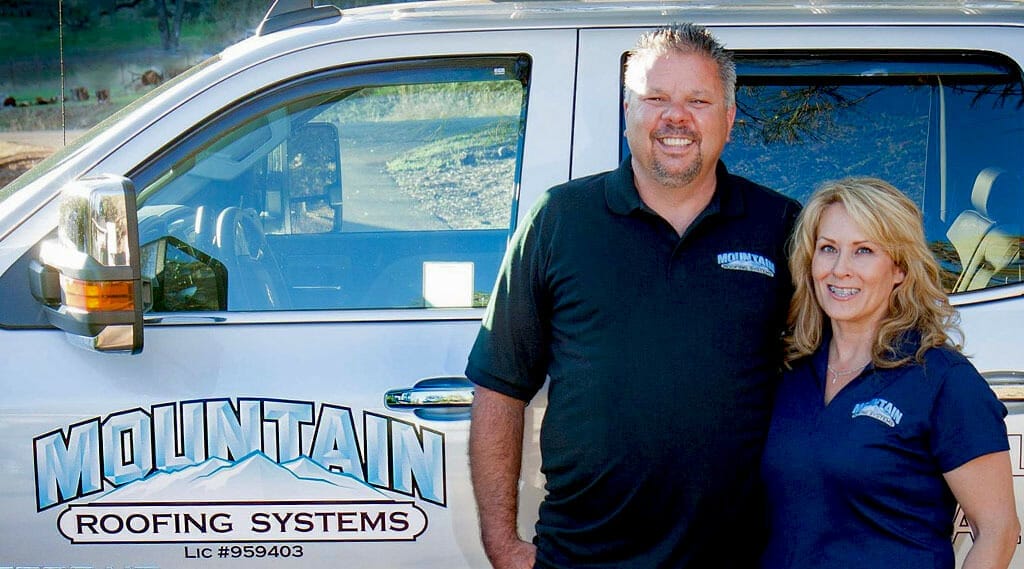 Mountain Roofing Systems owners standing in front of branded car