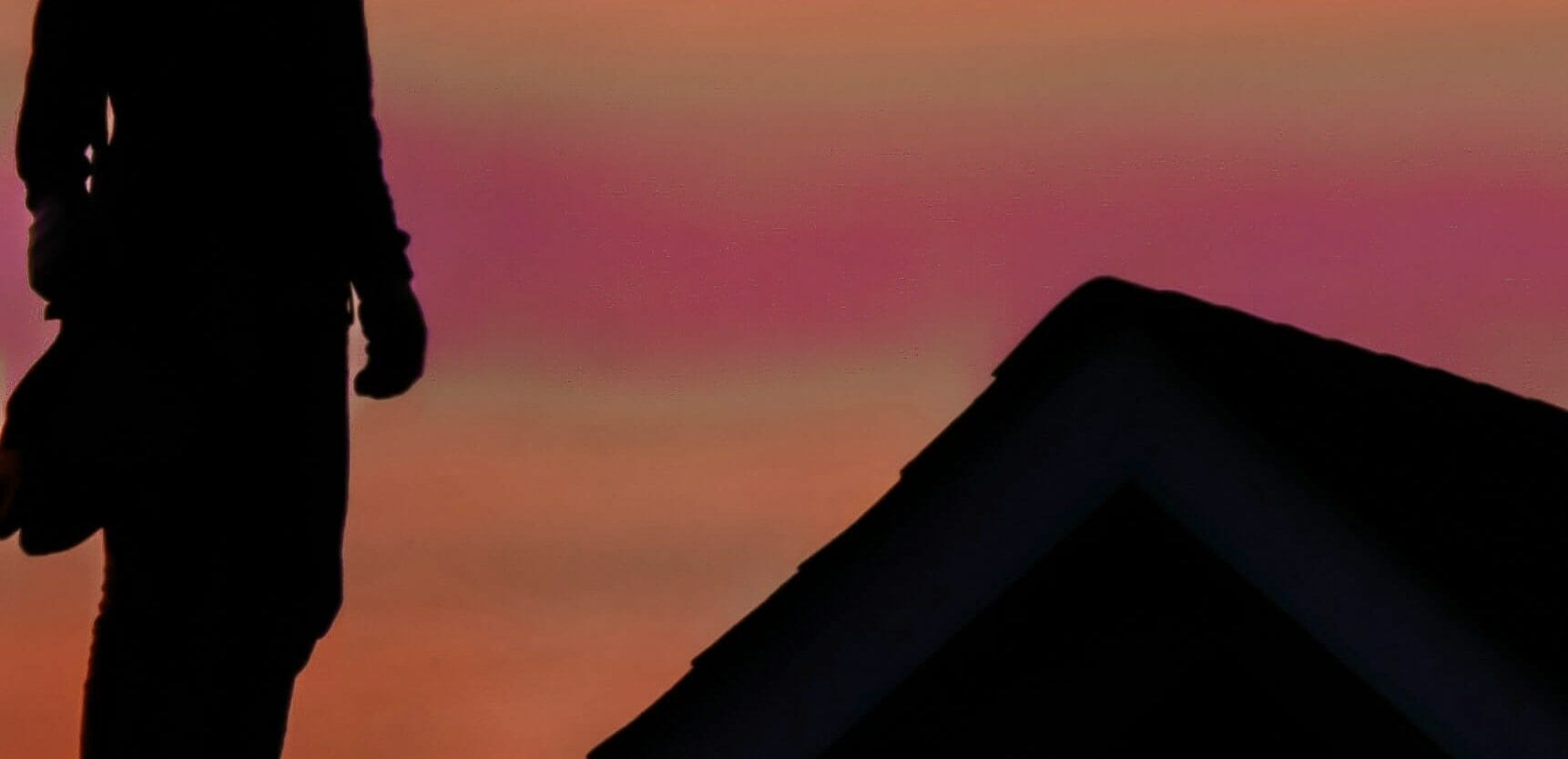 a man standing on a roof during sunset