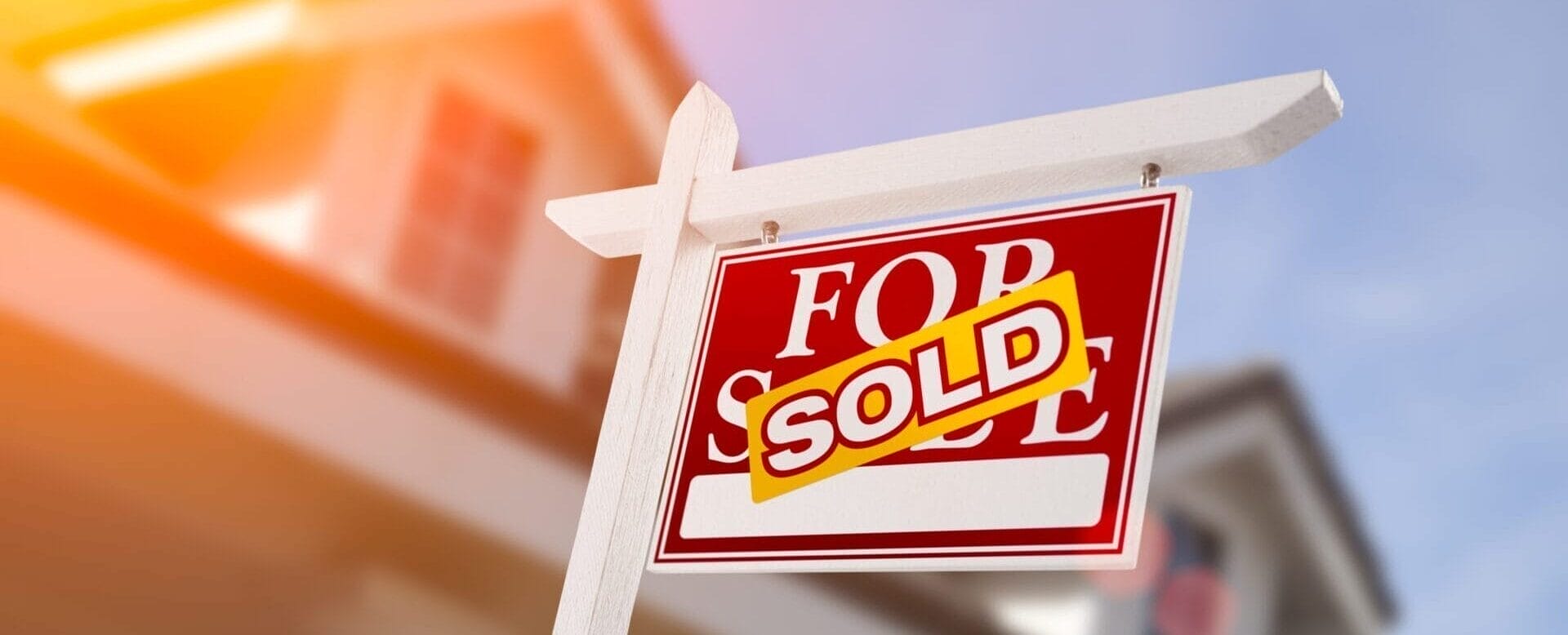 a sign saying sold in front of a house