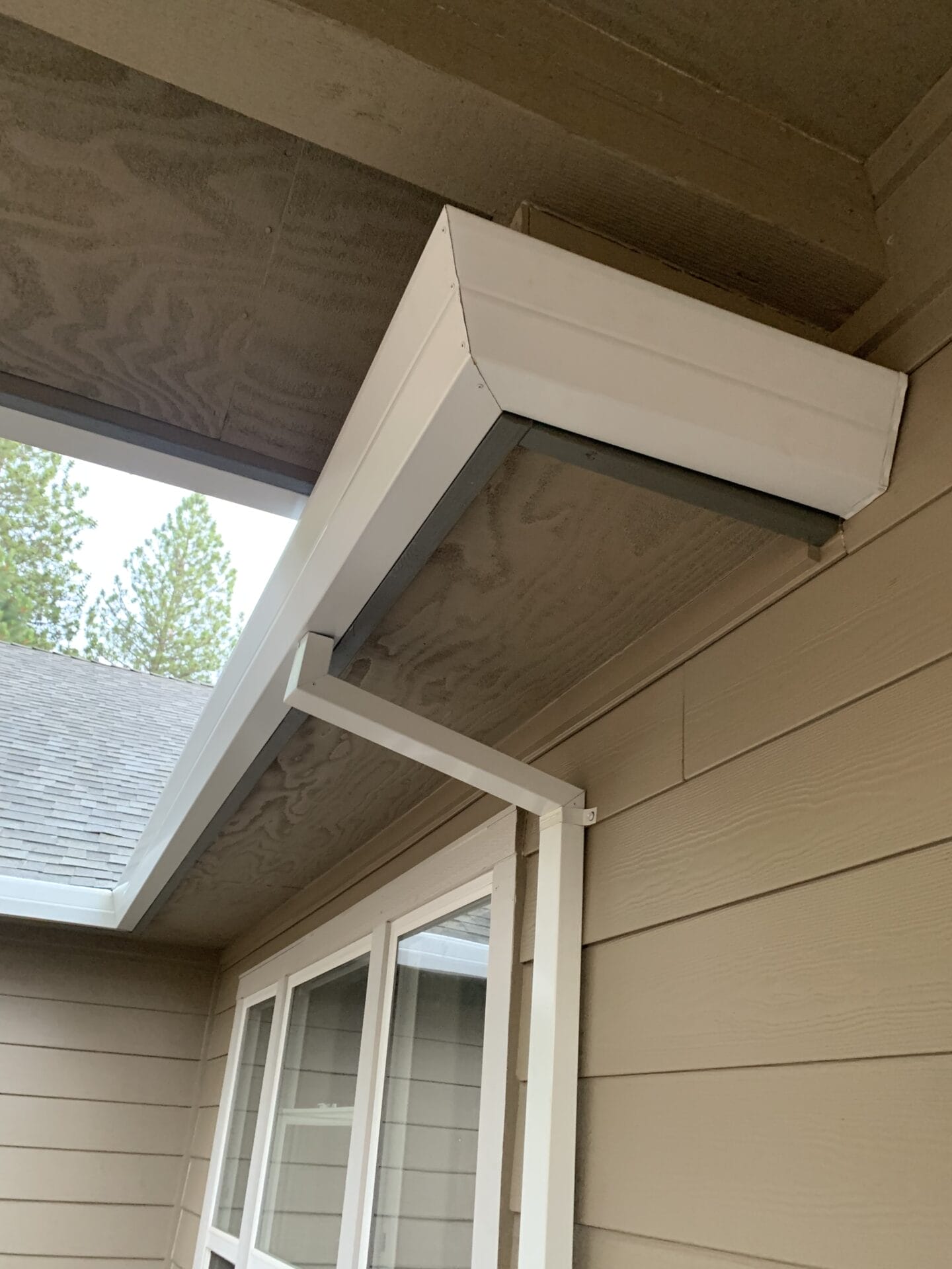 White seamless aluminum gutter installed on beige wood-paneled house exterior in Placerville, designed for effective rainwater drainage and home protection.