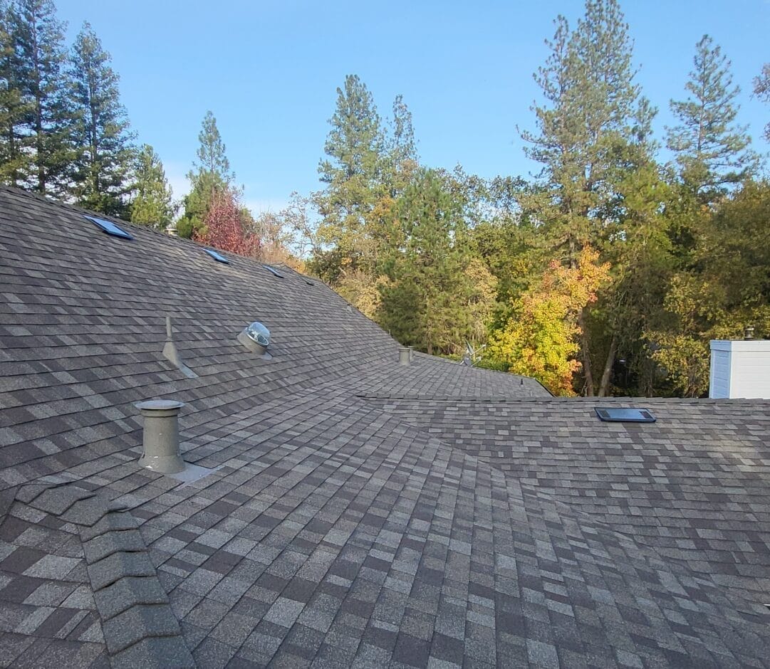 A wide view of a commercial roof with shingles, vents, and fixtures.