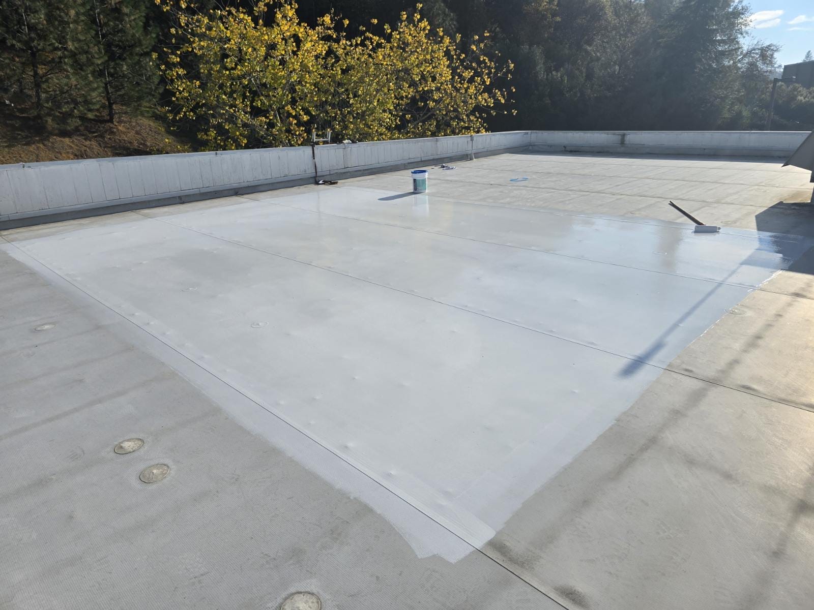 Commercial flat roof partially covered with a fresh white protective coating during restoration.